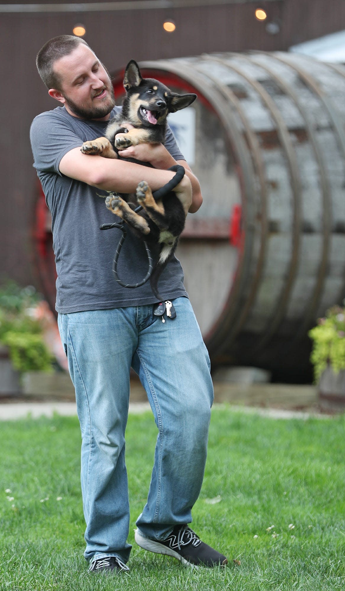 Adam Ryan carries Tucker, his Shepard mix puppy, at Yappy Hour Tuesdays at The Winery at Wolf Creek in Barberton.