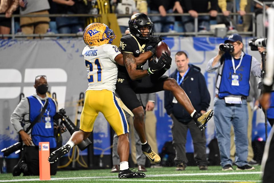 Wake Forest Demon Deacons wide receiver A.T. Perry (9) attempts a catch as Pittsburgh Panthers defensive back Damarri Mathis (21) defends in the first quarter of the ACC championship game at Bank of America Stadium.