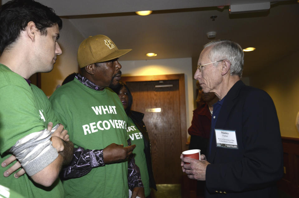 Reggie Rounds of Ferguson, Missouri (center), speaks to Federal Reserve Vice Chair Stanley Fischer (right), as Ady Barkan (left) looks on&nbsp;at Fed Up's inaugural event in August 2014 in Wyoming. (Photo: Bloomberg/Getty Images)