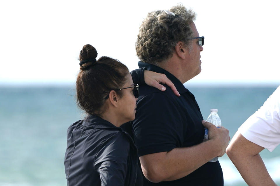 A couple, who asked not to be identified, stand on the beach near the Champlain Towers South Condo building, Saturday, June 26, 2021, in the Surfside area of Miami. The apartment building partially collapsed on Thursday. AP Photo/Lynne Sladky)