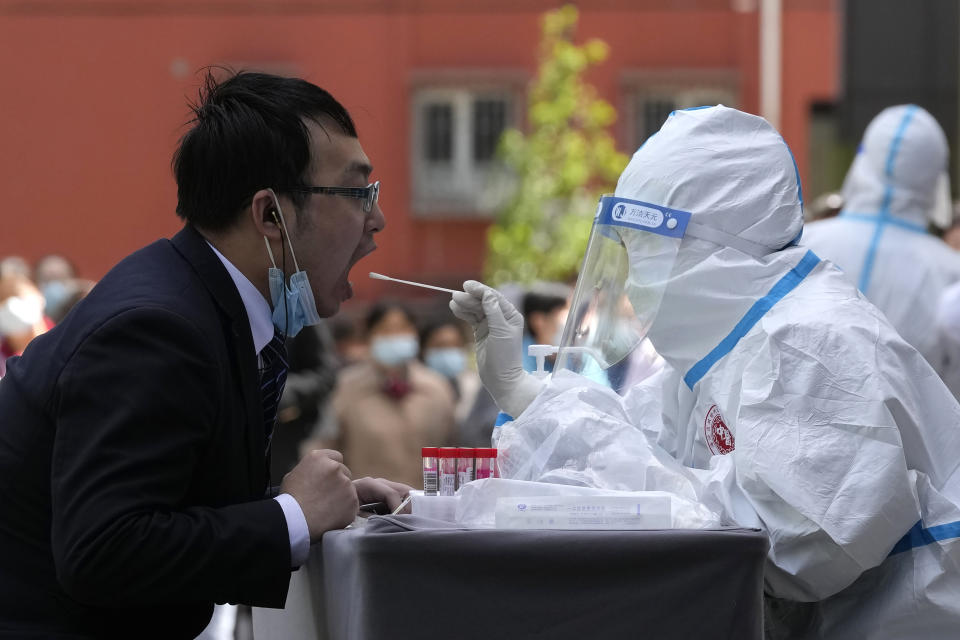 A worker gets swabbed for a COVID test outside a hotel in the Haidian district on Tuesday, April 26, 2022, in Beijing. China's capital Beijing is enforcing mass testing and closing down access to neighborhoods as it seeks to contain a new COVID-19 outbreak. (AP Photo/Ng Han Guan)