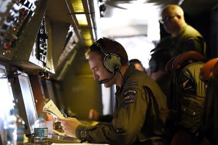 Information Manager Flight Lieutenant Stephen Graham studies notes aboard a Royal New Zealand Air Force (RNZAF) P3 Orion maritime search aircraft as it flies over the southern Indian Ocean looking for debris from missing Malaysian Airlines flight MH370 April 11, 2014. REUTERS/Richard Polden