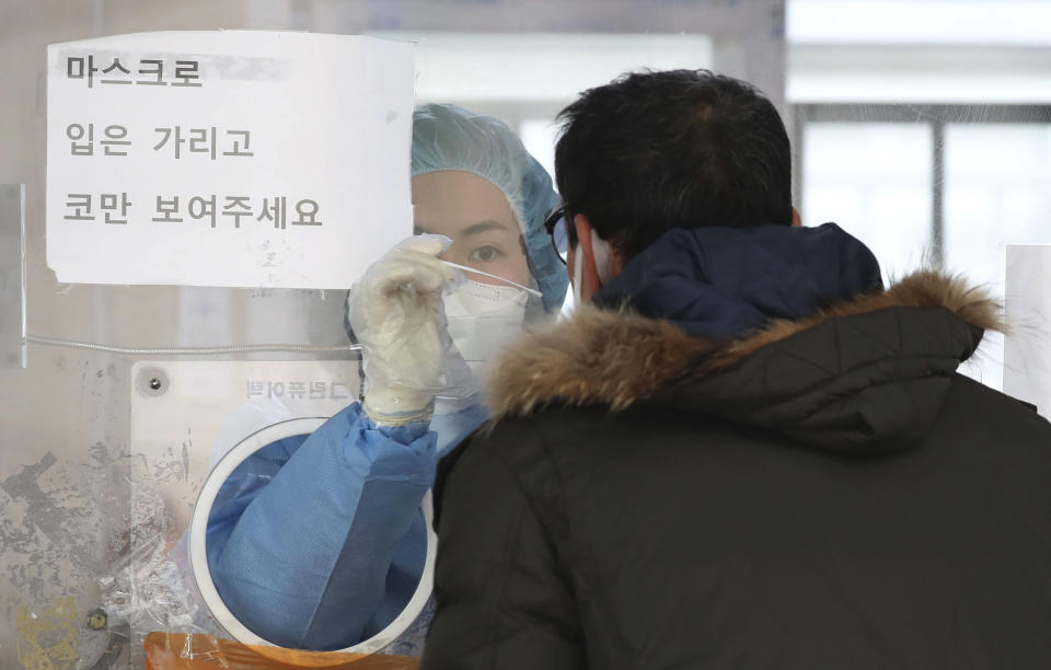 A medical worker wearing protective gear in a booth, takes sample from a man at a temporary screening clinic for the coronavirus in Seoul, South Korea, Saturday, Dec. 4, 2021. South Korea again broke its daily records for coronavirus infections and deaths and confirmed three more cases of the new omicron variant as officials scramble to tighten social distancing and border controls. (Park Mi-so/Newsis via AP)