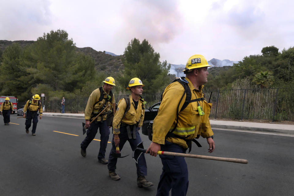 A fire crew walks in line to fight the Palisades Fire in the Pacific Palisades area of Los Angeles, Sunday, May 16, 2021. (AP Photo/Ringo H.W. Chiu)