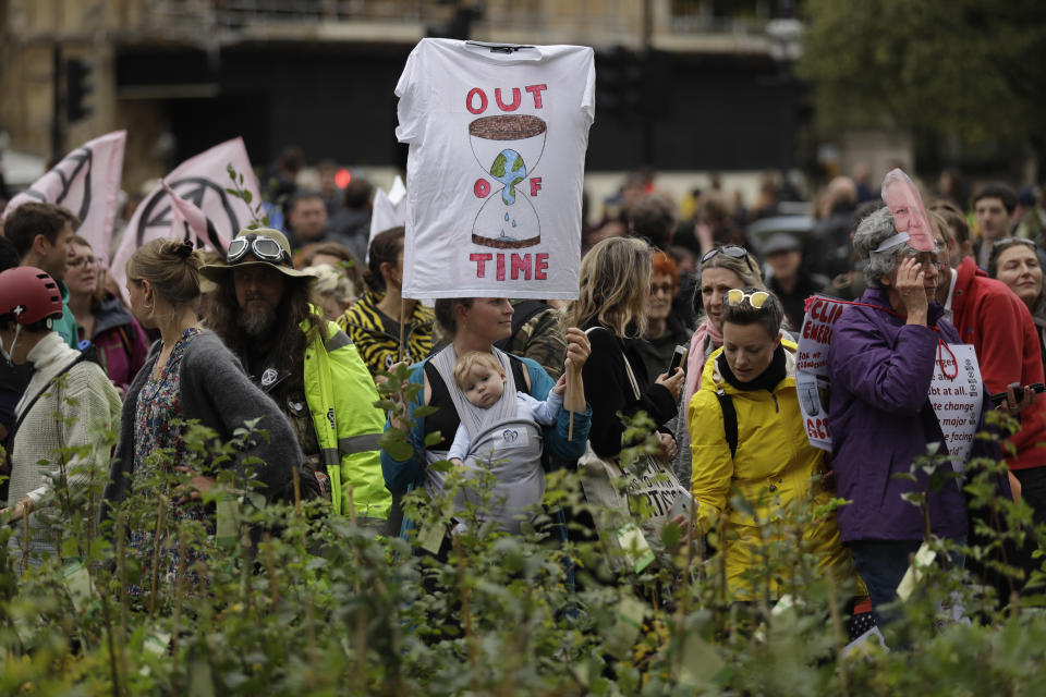 Extinction Rebellion climate change demonstrators stand by young trees in pots they placed opposite the Houses of Parliament in London, Tuesday, Oct. 8, 2019. Hundreds of climate change activists camped out in central London on Tuesday during a second day of world protests by the Extinction Rebellion movement to demand more urgent actions to counter global warming. (AP Photo/Matt Dunham)