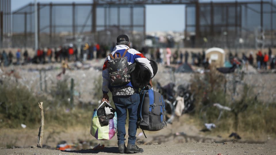 A migrant carries bags toward the US border fence from Ciudad Juarez, Mexico, on Wednesday. - Christian Chavez/AP