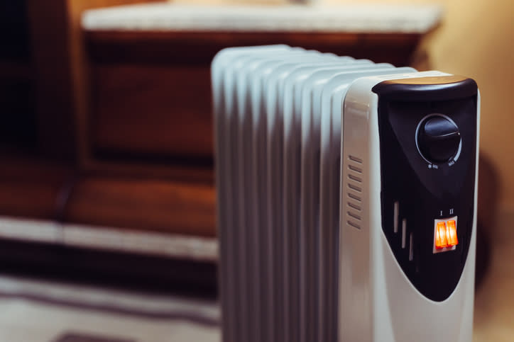 Electric radiator with adjustable thermostat knob on a living room floor