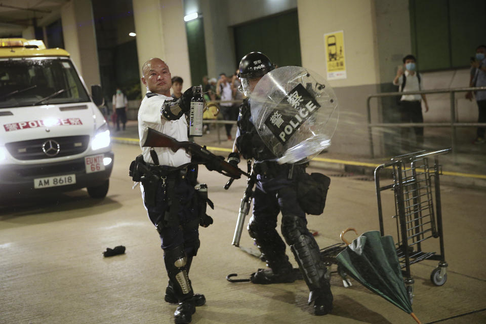 Hong Kong police officers use pepper gather against protesters during a crash near Kwai Chung police station as hundreds of protesters gather outside the police station to demand the authorities to release the protesters who have been detained with the charge of rioting during the recent protests, in Hong Kong, Tuesday, July 30, 2019. (Steve Leung/HK01 via AP)