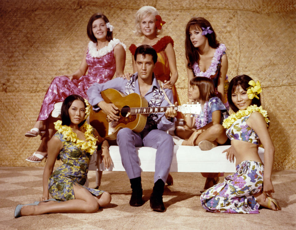 Elvis playing guitar while surrounded by women