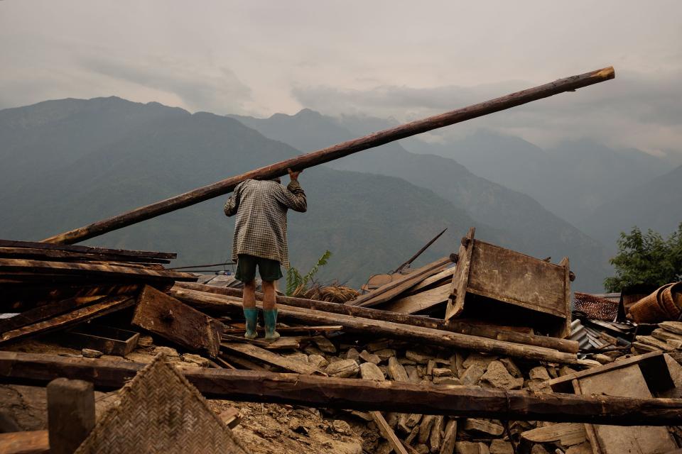 Nepal earthquake. Barpak, the epicenter of the earthquake. Funeral of Pur Bahadur Gurung, 26, who had just been dug out of the rubble. Saainli Gurung, his mother weeping. Scenes of villagers salvaging building materials and personal possessions. Dhan Raj Ghale, 30, dressed in mourning garb after the death of his wite, salvaging buildings materials and possessions from his house. by James Nachtwey