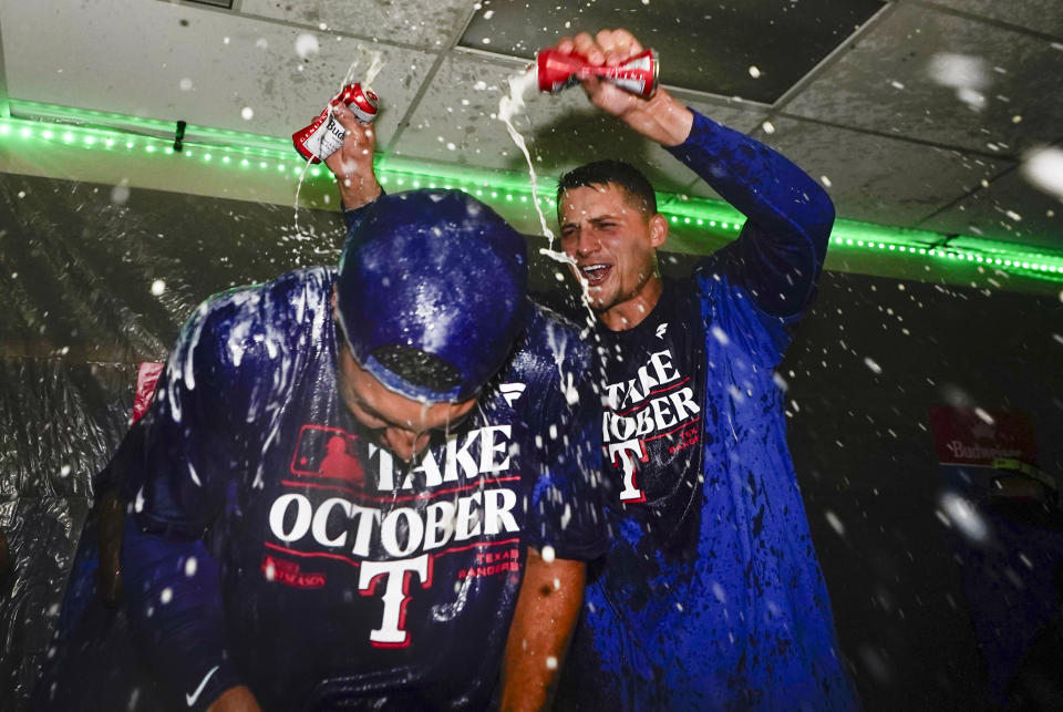 Texas Rangers second baseman Marcus Semien, left, has beer poured on him by shortstop Corey Seager, right, as they celebrate clinching a playoff spot in the American League after a 6-1 win over the Seattle Mariners in a baseball game, Saturday, Sept. 30, 2023, in Seattle. (AP Photo/Lindsey Wasson)