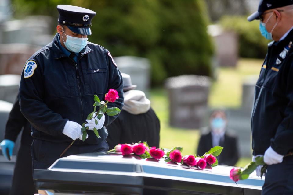 Firefighter Rubio Alfaro places a rose on the casket of Israel Tolentino, 33, a fellow firefighter, on April 2, 2020. Tolentino died from complications of COVID-19.