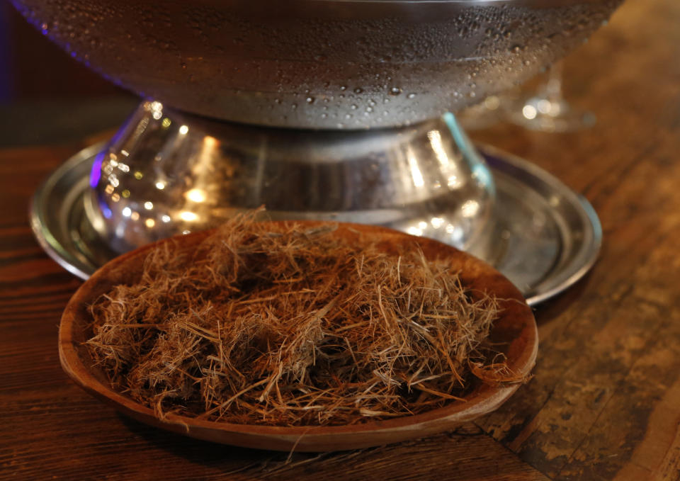 A sample of elephant dung is shown at a gin tasting session at the Botlierskop Private Game Reserve, near Mossel Bay, South Africa, Monday, Oct. 23, 2019. After about five sizeable bags of dung are collected for a batch of 3,000 to 4,000 bottles of the gin, the droppings are dried and crumbled, then washed to remove dirt and sand. Eventually only the remains of the fruits, flowers, leaves and bark eaten by the elephants are left behind. (AP Photo/Denis Farrell)