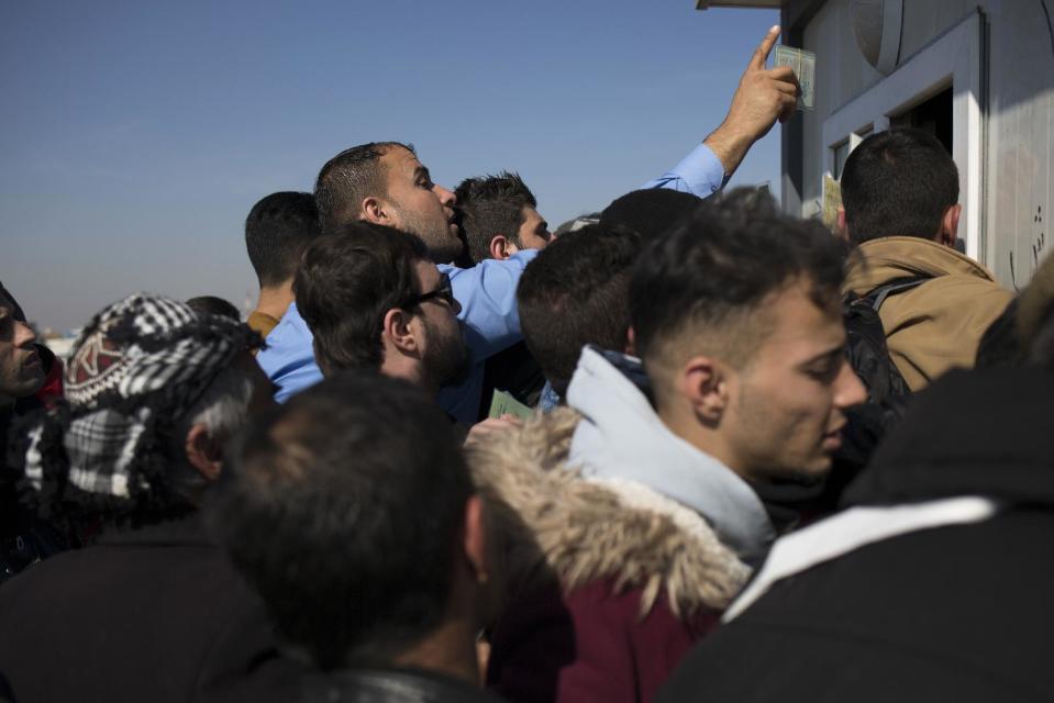 A man reaches out with his ID card to receive a permission from Kurdish officials to cross the Khazer checkpoint on their way to Mosul, Tuesday Feb. 7, 2017. The United Nations says some 30,000 people have returned to neighborhoods in Mosul retaken from the Islamic State group since the operation to push the militants from the city was officially launched in October. (AP Photo/Bram Janssen)