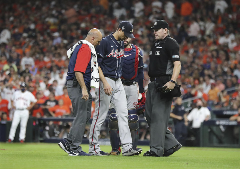 Braves starting pitcher Charlie Morton walks off the field with a team trainer after after suffering a fractured right fibula against the Astros in game 1 of the World Series on Tuesday, Oct. 26, 2021, in Houston. (Curtis Compton/Atlanta Journal-Constitution via AP)