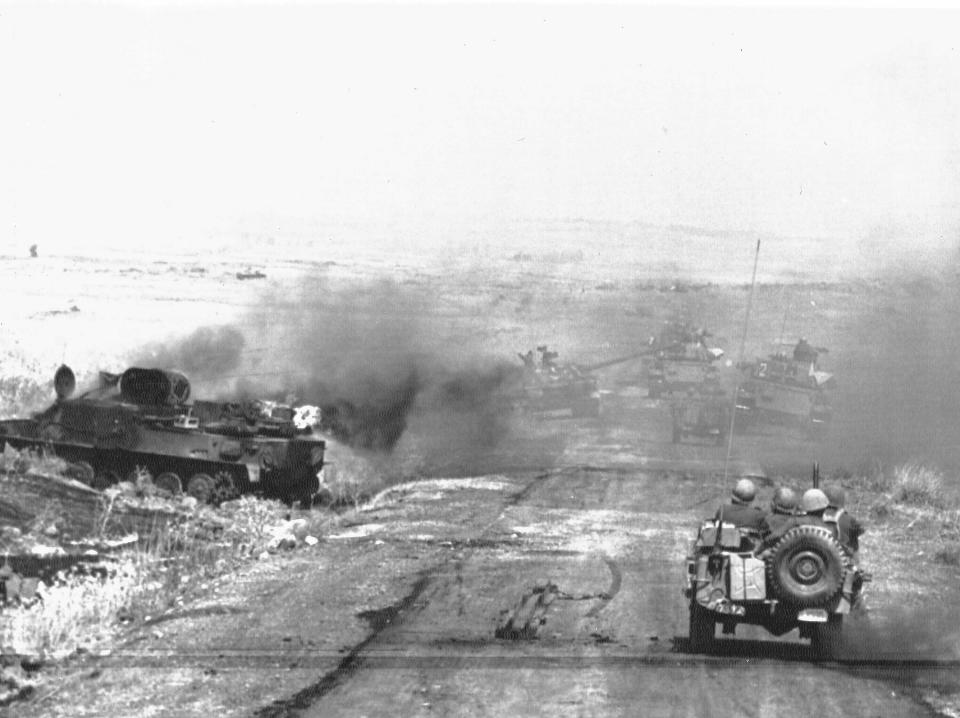 FILE - In this Oct. 9, 1967, file photo, an Israeli column passes a burning Syrian tank in the Golan Heights as they head toward the fighting on the Israeli-Syrian front. The Golan Heights is a strategic high ground at the southwestern corner of Syria with stunning broad views of both Israel and Syria below. Israel captured the territory in the 1967 Mideast War and annexed it in 1981, a move that was never recognized by any country in the world. (AP Photo/File)