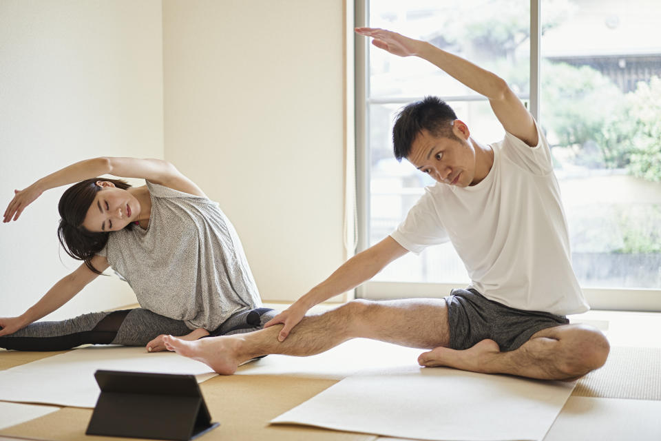 Couple exercising with a digital tablet in the Japanese-style room at home. (Photo: Getty)