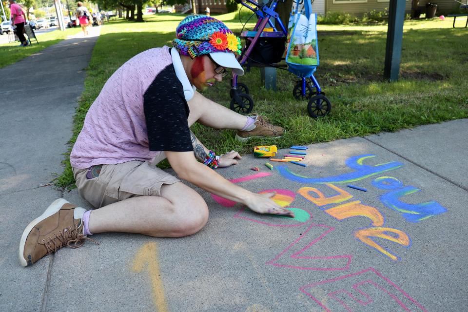 Malachi Wonderland marks his first Rochester Pride Parade as an out trans man by scrawling the message "You are loved" in chalk on a sidewalk.