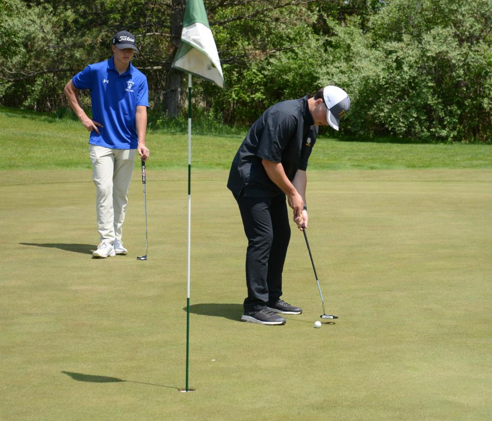 Flat Rock's Ben Scully putts as Jack Salenbien of Dundee watches during the Monroe County Championship Monday.