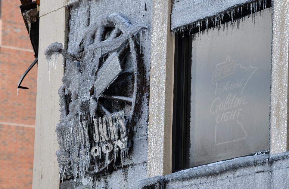 The Cowboy Jack's Saloon sign is encased in ice Tuesday, Feb. 18, 2020, after a fire destroyed the Press Bar next door Monday. 