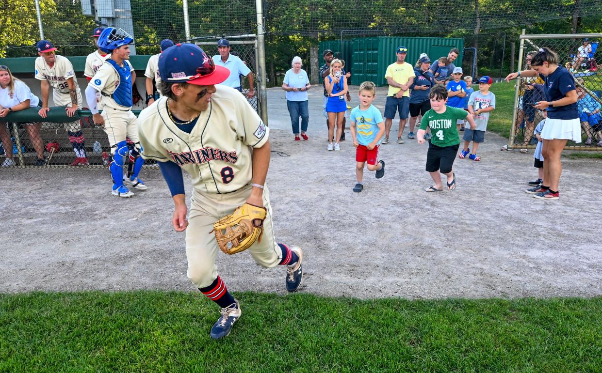 Harwich Mariners third baseman Jake Ogden leads young fans out on the field on Monday at Whitehouse Field in Harwich for the national anthem before the game against the Chatham Anglers.