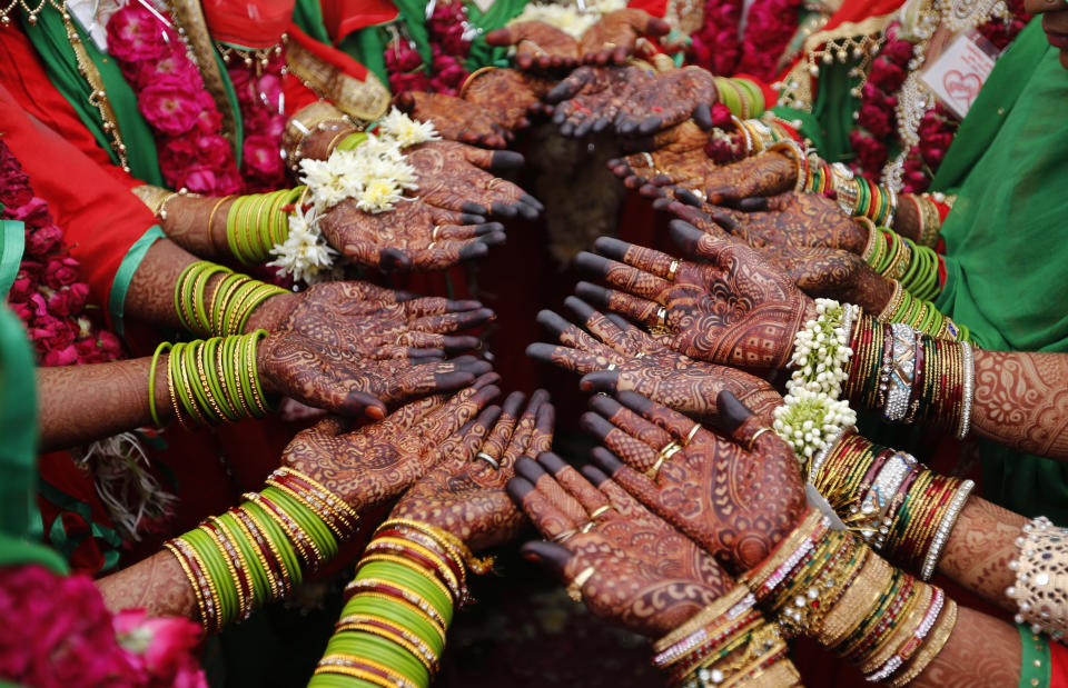 In this Sunday, Nov. 4, 2018, file photo, Indian Muslim brides display henna designs on their hands during a mass marriage in Ahmadabad, India. Thirty five couples were married off in a mass marriage ceremony. Mass weddings in India are organized by social organizations primarily to help the economically backward families who cannot afford the high ceremony costs as well as the customary dowry and expensive gifts that are still prevalent in many communities. (AP Photo/Ajit Solanki, File)