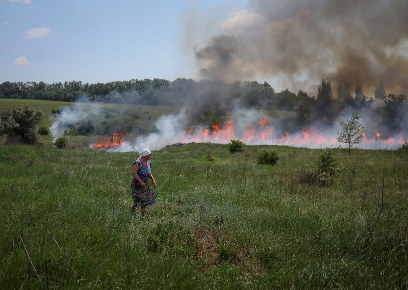 Una residente local mira la hierba que está en llamas después de un bombardeo, en medio del ataque de Rusia a Ucrania, cerca de la ciudad de Bakhmut, región de Donetsk, Ucrania