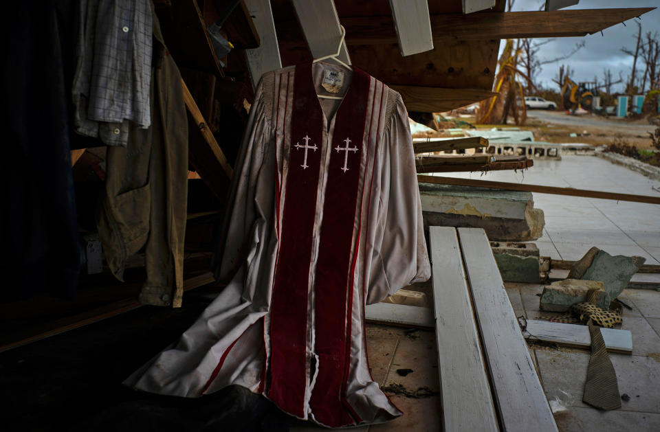 Priest's mass vestments hang in the rubble of a destroyed house by Hurricane Dorian in Pelican Point, Grand Bahama, Bahamas, Sept. 14, 2019. | Ramon Espinosa—AP