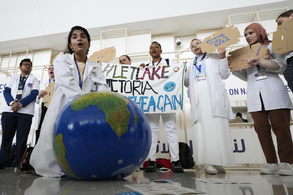 A woman pretends to resuscitate the Earth during a demonstration at the COP28 U.N. Climate Summit, Sunday, Dec. 3, 2023, in Dubai, United Arab Emirates. (AP Photo/Peter Dejong)