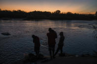 A migrant family stands on the shore of the Rio Grande before crossing from Ciudad Acuña, Mexico, into Del Rio, Texas, at sunrise Sunday, Sept. 19, 2021. (AP Photo/Felix Marquez)