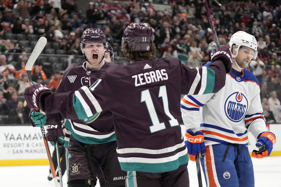 Anaheim Ducks left wing Max Jones, left, celebrates his goal with center Trevor Zegras, center, as Edmonton Oilers left wing Warren Foegele skates away during the first period of an NHL hockey game Sunday, Dec. 31, 2023, in Anaheim, Calif. (AP Photo/Mark J. Terrill)