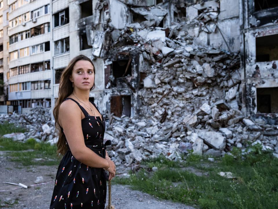 Woman standing in front of ruins in Ukraine.