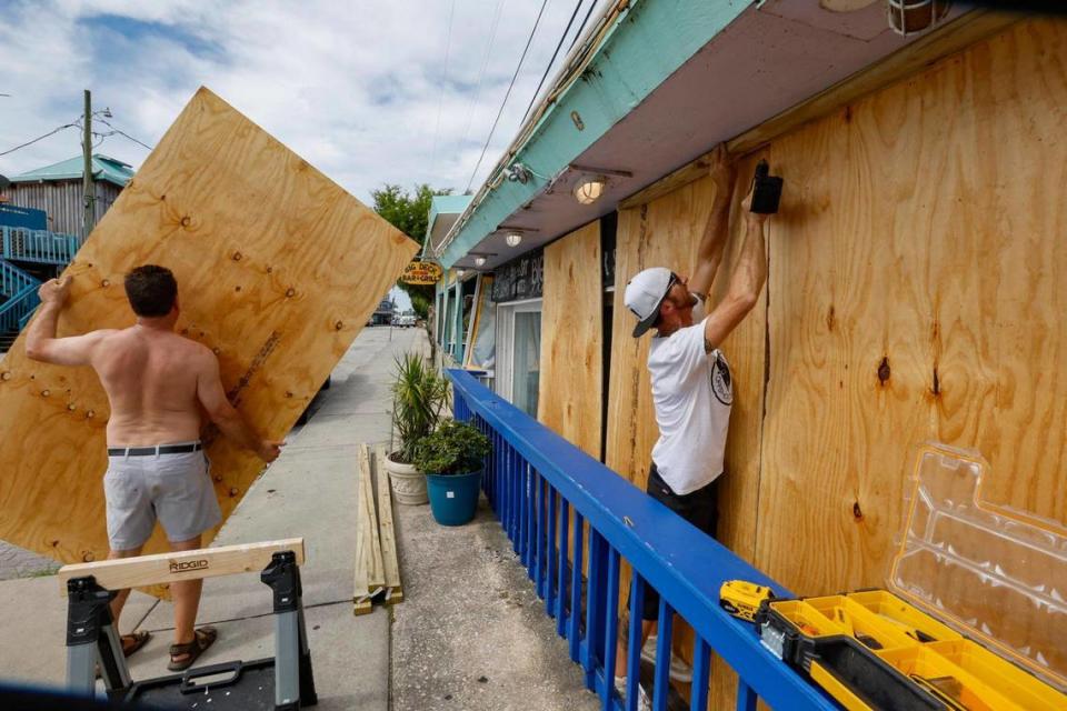 Jeff Wigsten y Bobby Touchton, de izquierda a derecha, tapiando Big Deck Raw Bar en Cedar Key, la Florida, en preparación para el huracán Idalia el martes 29 de agosto de 2023. el martes 29 de agosto de 2023.