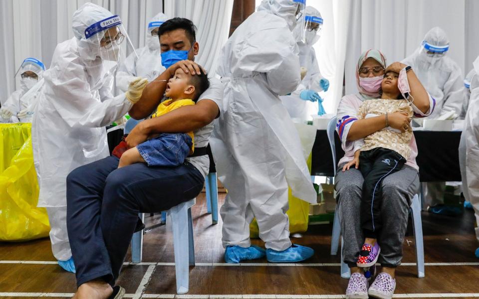 Parents comfort their children as medical personnel collect swab samples for Covid-19 testing in Selangor - FAZRY ISMAIL/EPA-EFE/Shutterstock