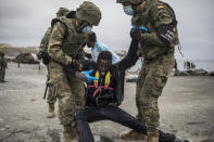 A man is held by soldiers of the Spanish Army at the border of Morocco and Spain, at the Spanish enclave of Ceuta, on Tuesday, May 18, 2021. Ceuta, a Spanish city of 85,000 in northern Africa, faces a humanitarian crisis after thousands of Moroccans took advantage of relaxed border control in their country to swim or paddle in inflatable boats into European soil. Around 6,000 people had crossed by Tuesday morning since the first arrivals began in the early hours of Monday, including 1,500 who are presumed to be teenagers. (AP Photo/Javier Fergo)