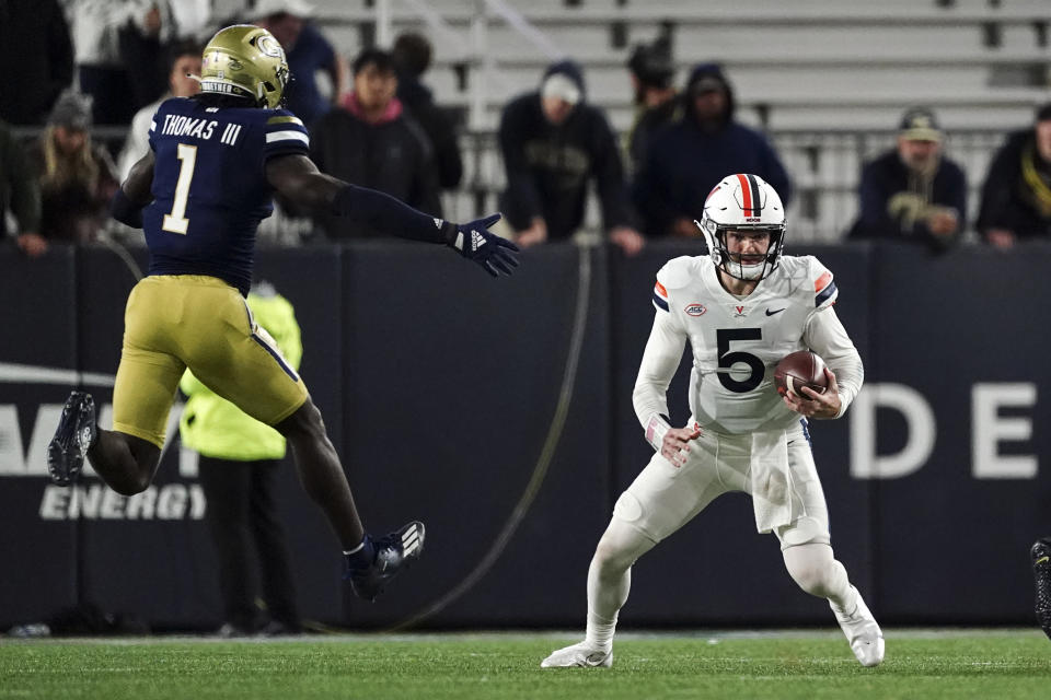 Virginia quarterback Brennan Armstrong (5) scrambles under pressure from Georgia Tech linebacker Charlie Thomas (1) during the second half of an NCAA college football game Thursday, Oct. 20, 2022, in Atlanta. (AP Photo/John Bazemore)