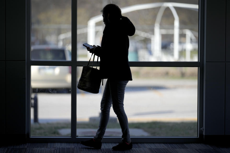 A woman looks at her phone before the start of an Iowa Migrant Movement for Justice informational meeting, Wednesday, March 27, 2024, in Des Moines, Iowa. A bill in Iowa that would allow the state to arrest and deport some migrants is stoking anxiety among immigrant communities about how it would be interpreted and enforced. (AP Photo/Charlie Neibergall)