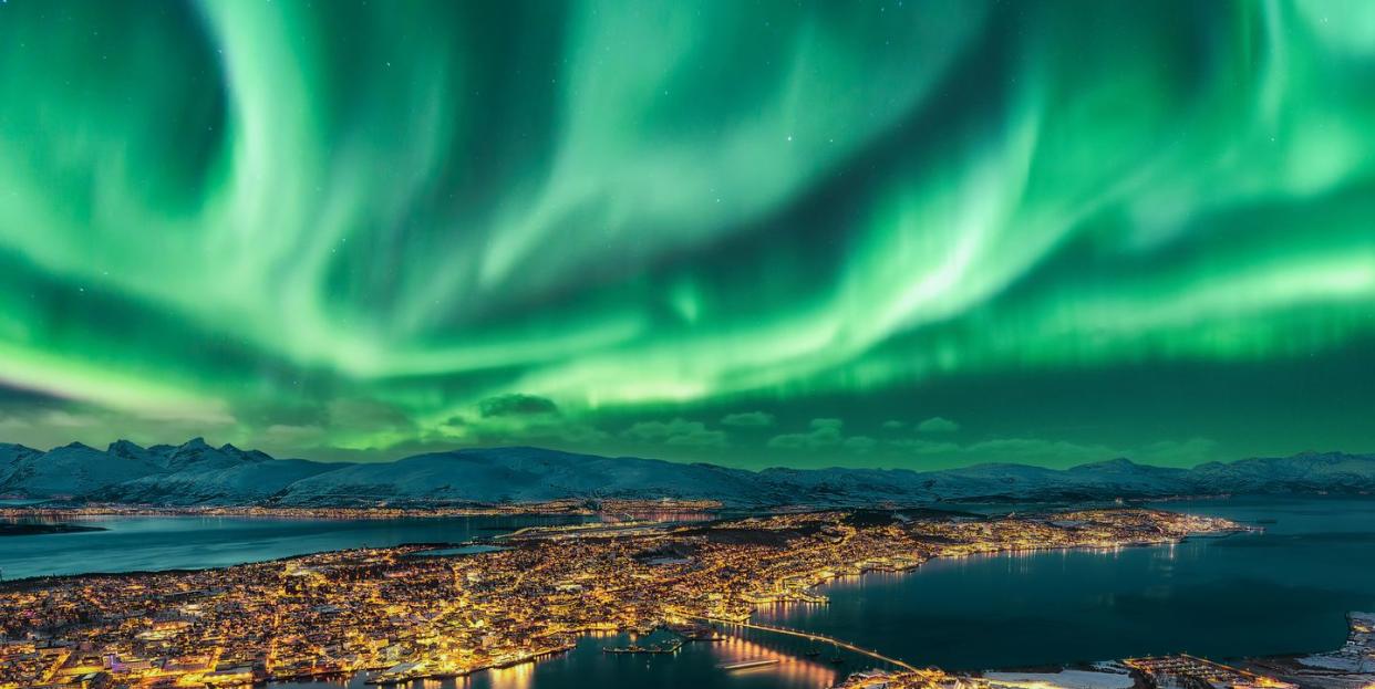 aurora borealis dancing over tromso urban skyline, northern norway