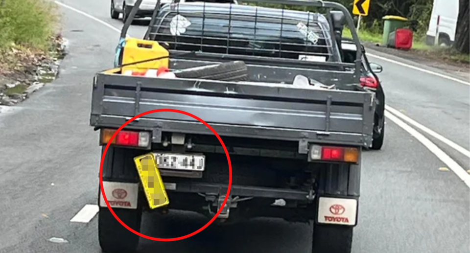 A NSW ute driver sporting two number plates, with a yellow and black one hanging loose to reveal another plate underneath.