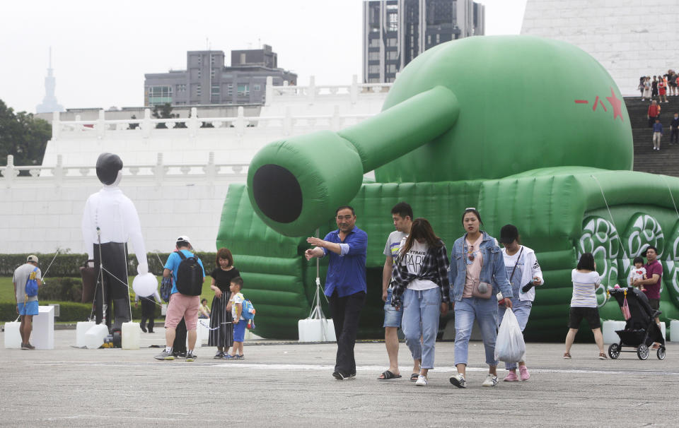 Chinese tourists walk past an inflatable tank man at the Liberty Square of Chiang Kai-shek Memorial Hall in Taipei, Taiwan, Saturday, June 1, 2019. An artist erected the inflatable display in Taiwan’s capital to mark an iconic moment in the Tiananmen Square pro-democracy protests. The larger-than-life balloon installation, which stands in front of Taipei’s famous hall, portrays a peaceful encounter between a Chinese civilian and the military tanks that contributed to a brutal shutdown of the demonstrations in Beijing on June 4, 1989. (AP Photo/Chiang Ying-ying)