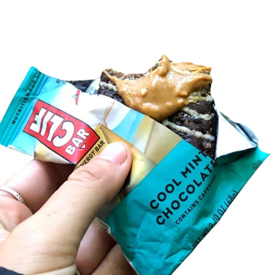 The writer holds a half-eaten Clif bar with blue packaging and "Cool Mint Chocolate" text on it