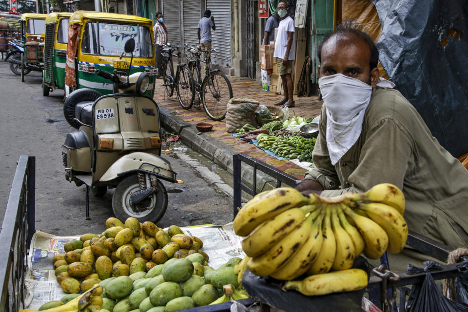 A street side fruit vendor has his face covered as a precaution against the coronavirus in Kolkata, India, Tuesday, July 21, 2020. With a surge in coronavirus cases in the past few weeks, state governments in India have been ordering focused lockdowns in high-risk areas to slow down the spread of infections. (AP Photo/Bikas Das)