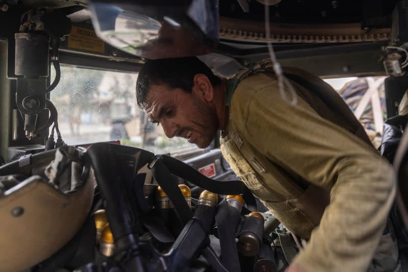 Members of Afghan Special Forces travelling in a humvee destroyed during heavy clashes with Taliban take cover during the rescue mission of a policeman besieged at a check post, in Kandahar province