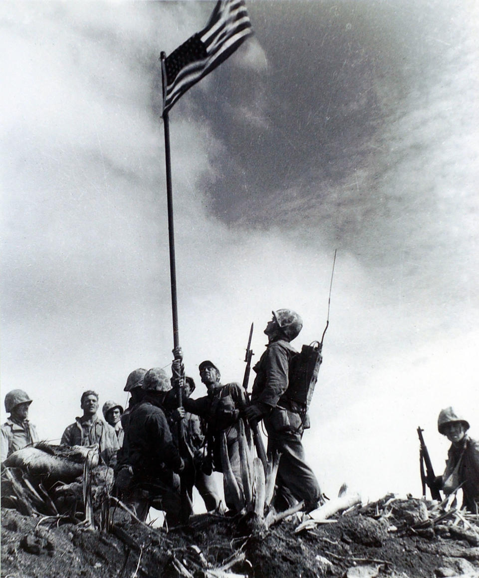 FILE - In this Feb. 23, 1945, file photo provided by the U.S. Marine Corps, Marines from the 5th Division of the 28th Regiment gather around a U.S. flag they raised atop Mt. Suribachi on Iwo Jima during World War II. This was the first flag raised by the Marine Corps at Iwo Jima. The Pacific War was so massive and so calamitous that it can be difficult to put it in context. There was the Marco Polo Bridge Incident that triggered the Sino-Japanese War, the Battle of Midway that changed the course of the war and the dramatic flag-raising on Iwo Jima. (Sgt. Louis R. Lowery/U.S. Marine Corp via AP File)