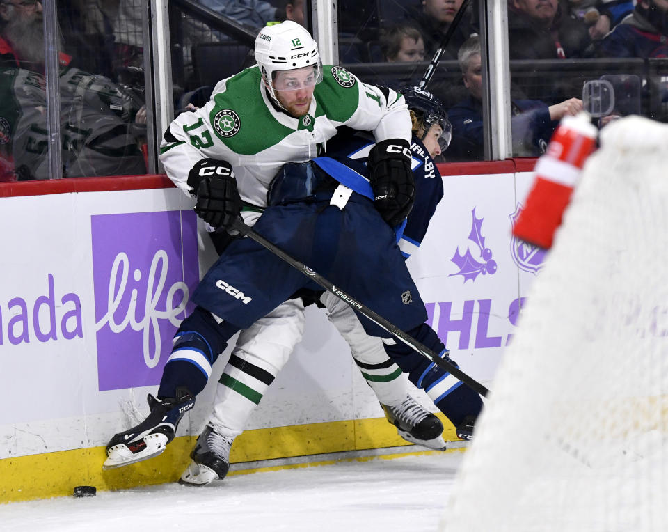 Dallas Stars' Radek Faksa (12) is tied up by Winnipeg Jets' Axel Jonsson-Fjallby (71) during the second period of an NHL hockey match in Winnipeg, Manitoba, on Tuesday, Nov. 28, 2023. (Fred Greenslade/The Canadian Press via AP)