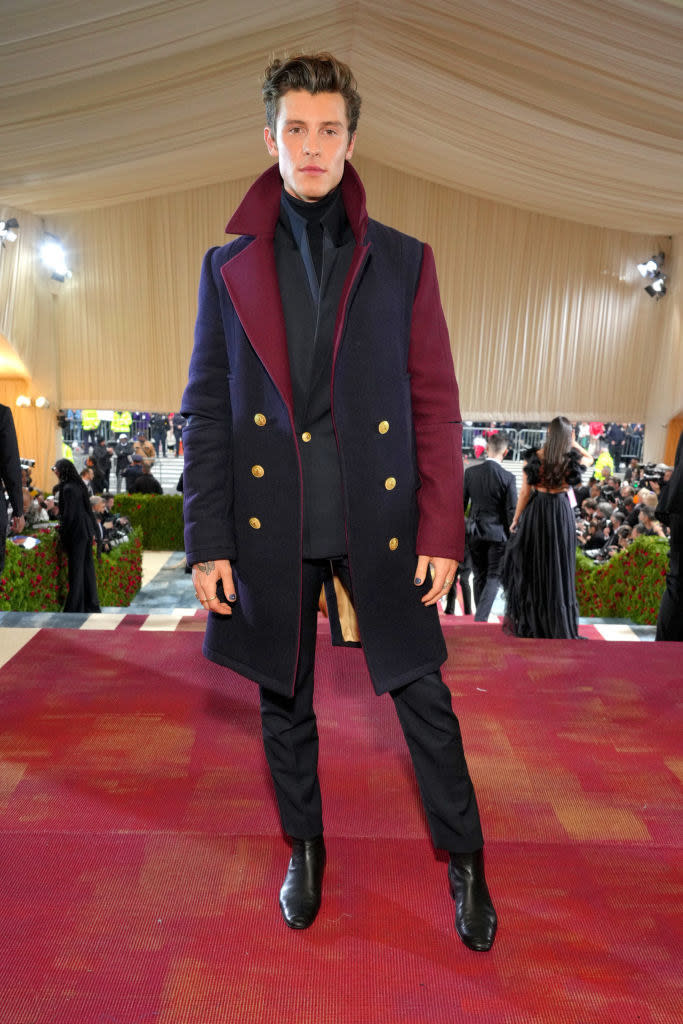 Shawn Mendes wearing a multicolored overcoat over a dark suit