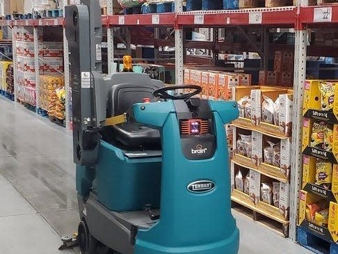 A floor-scrubbing robot rolls through an aisle at Sam's Club