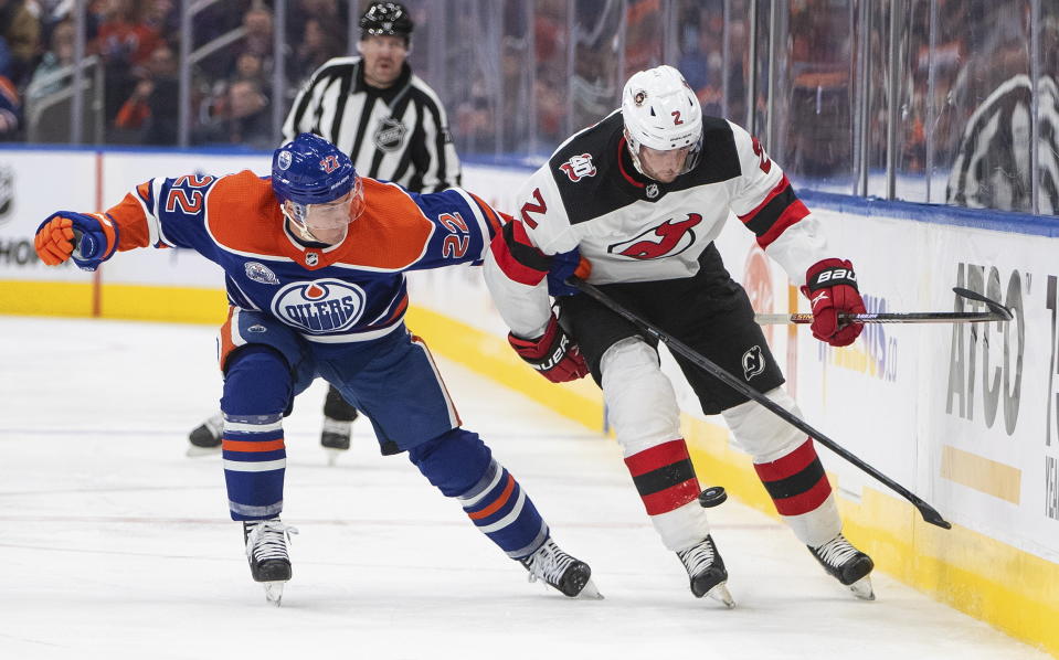 New Jersey Devils' Brendan Smith (2) and Edmonton Oilers' Tyson Barrie (22) compete for the puck during the third period of an NHL hockey game Thursday, Nov. 3, 2022, in Edmonton, Alberta. (Jason Franson/The Canadian Press via AP)