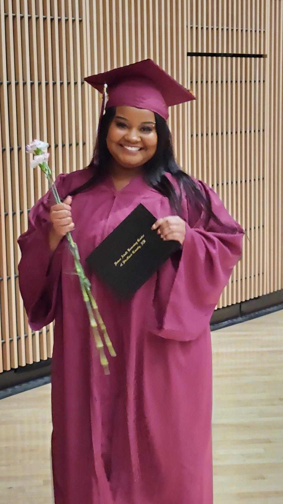 Just one of many very excited graduates, Jasmin Baldwin, receives her certificate and two carnations. Students were asked to keep one flower and give one to a person who has supported their educational journey.