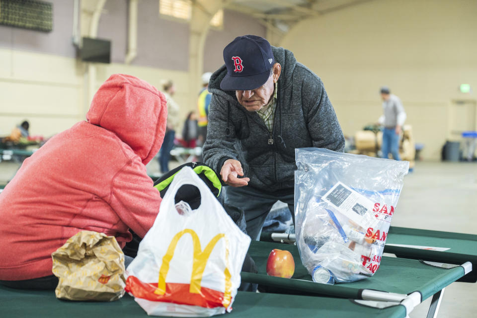 A couple rests at an evacuation center at Santa Cruz County fairgrounds in Watsonville, Calif., Saturday, March 11, 2023. (AP Photo/Nic Coury)